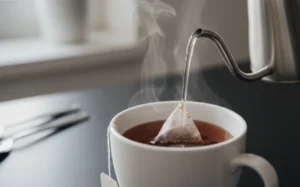 正在沖泡紅茶的過程，熱水注入茶杯中，茶色呈現琥珀色